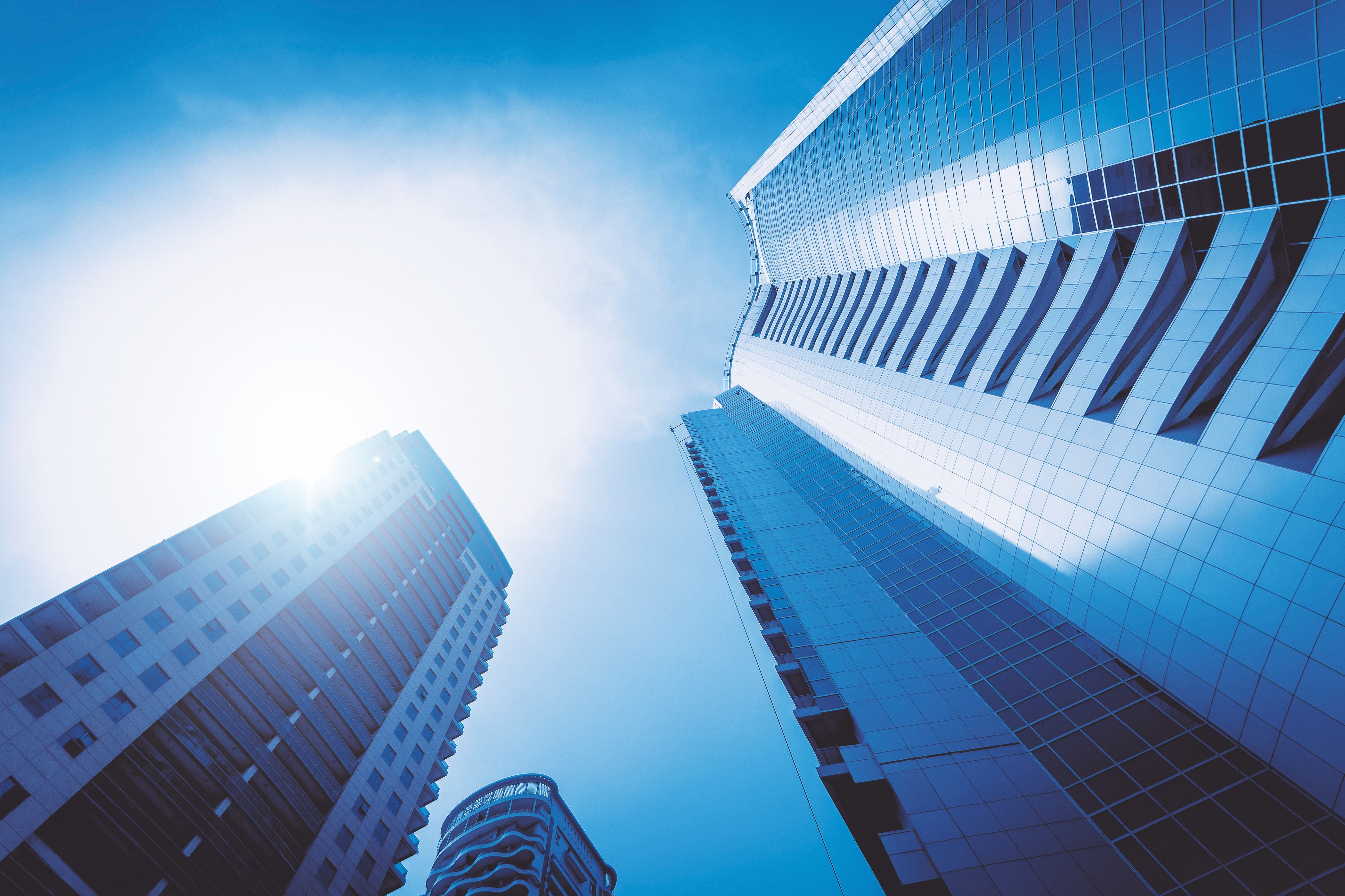 Glass office towers rising against a blue sky